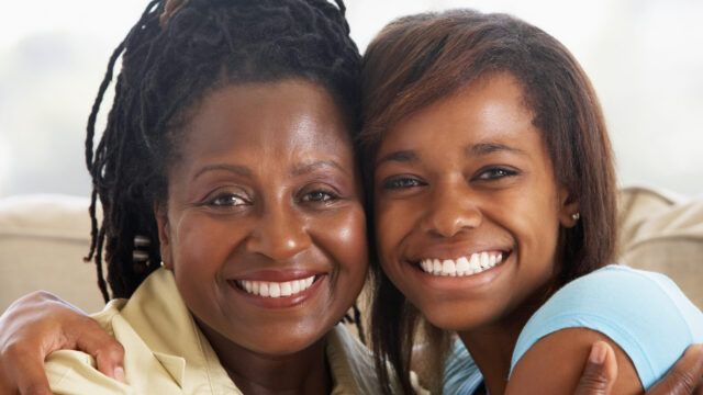 Mother and teen daughter hugging and smiling at the camera