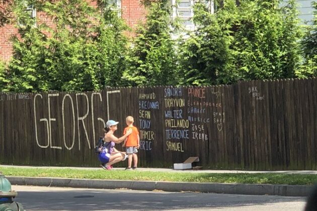 Mother and son reflecting by George Floyd memorial fence.