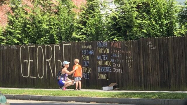 Mother and son reflecting by George Floyd memorial fence