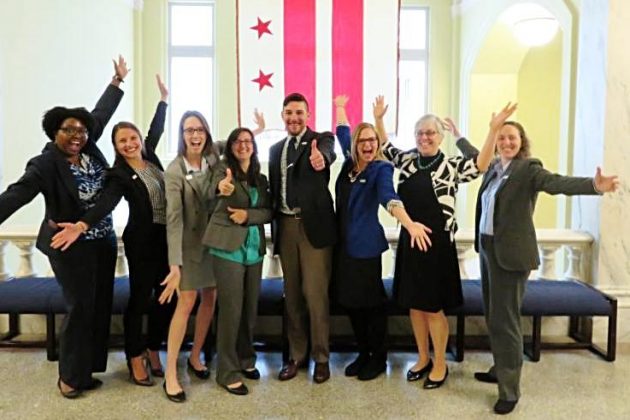 Children's Law Center staff smiling in front of DC flag.