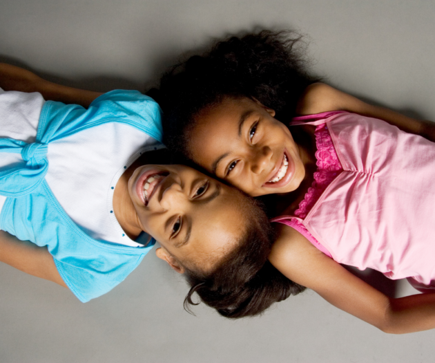 Photo of sisters lying on the ground together, smiling.